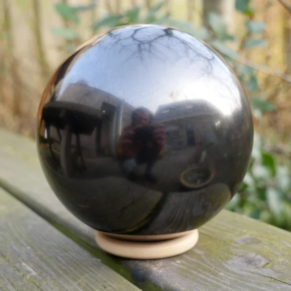 Fraaie glanzende shungiet bol met diameter van ruim 13cm op houten ring